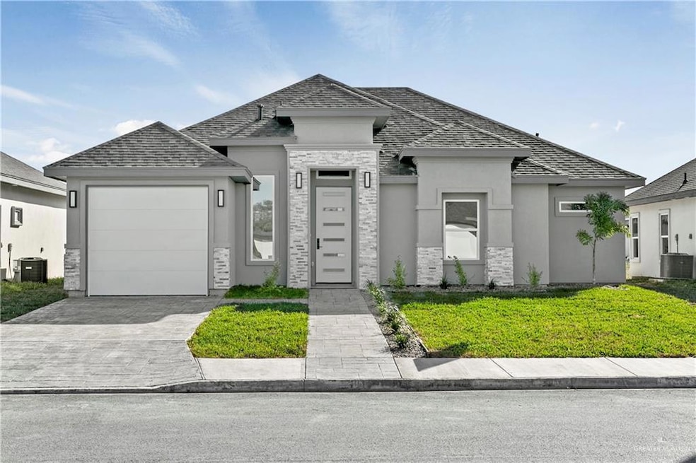View of front of house featuring central air condition unit, a front yard, and a garage