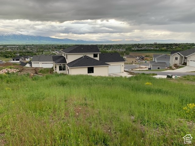 View of front of home with stucco siding, a garage, a mountain view, and a residential view