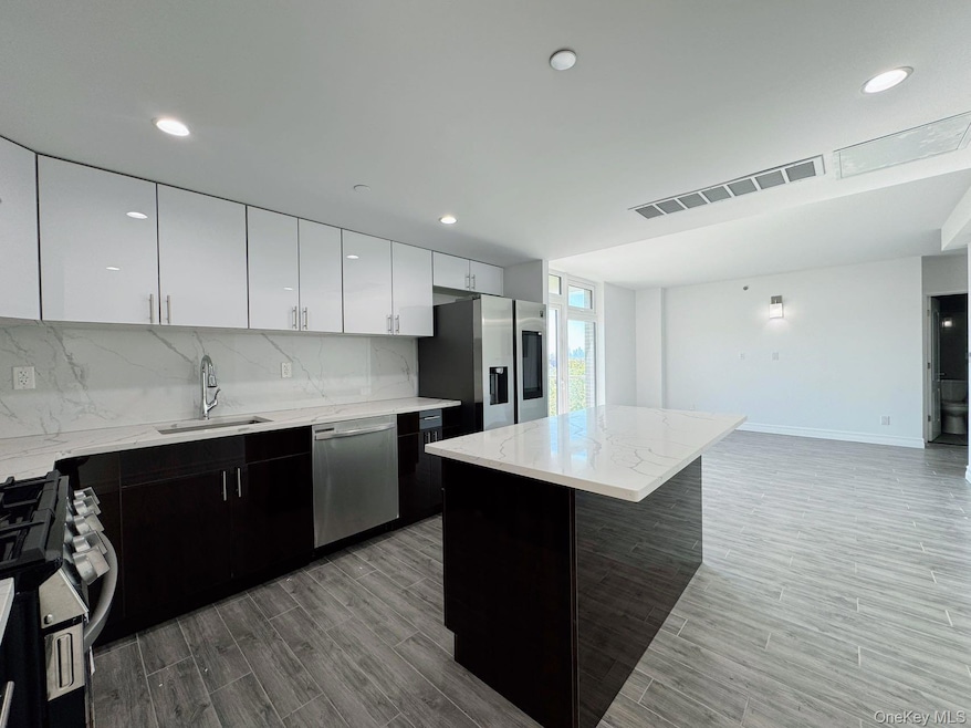 Kitchen with decorative backsplash, visible vents, appliances with stainless steel finishes, a sink, and a center island