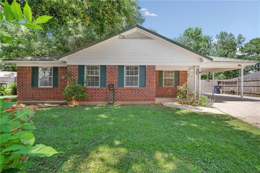 View of front of house featuring brick siding, an attached carport, and driveway