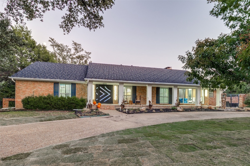 This inviting ranch-style home offers classic charm with a circular drive and a spacious covered front porch.
