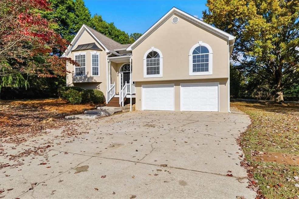 Bi-level home featuring concrete driveway, a garage, and stucco siding