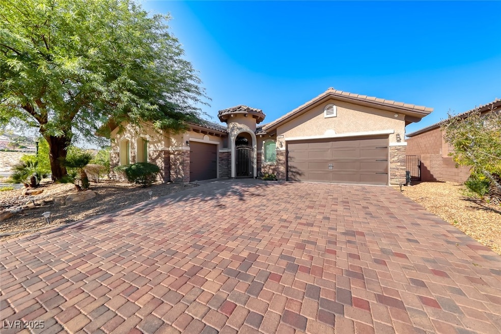 Mediterranean / spanish house featuring stone siding, an attached garage, decorative driveway, stucco siding, and a tile roof