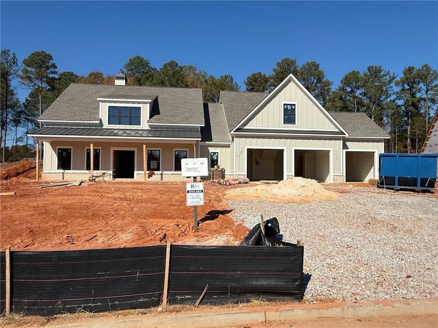 View of front of house with board and batten siding, roof with shingles, a porch, and a garage