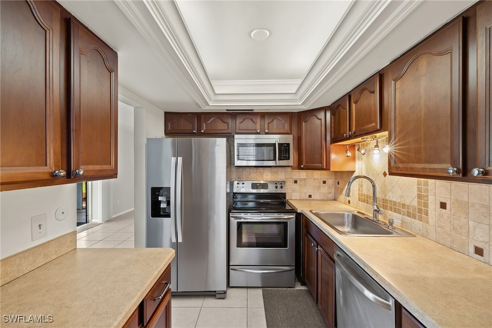 Kitchen with a sink, a tray ceiling, appliances wi