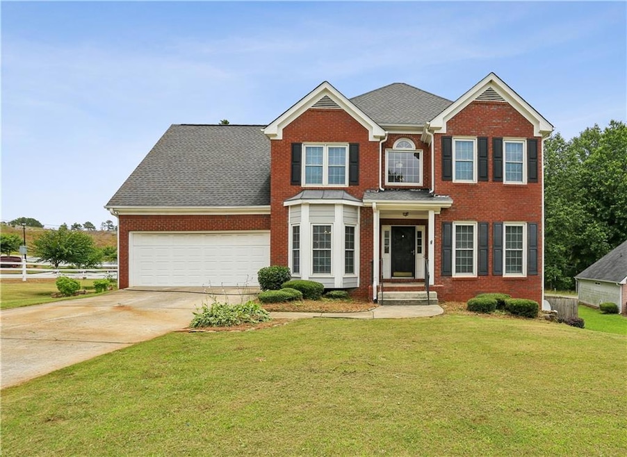 View of front of home featuring an attached garage, brick siding, a front yard, and concrete driveway