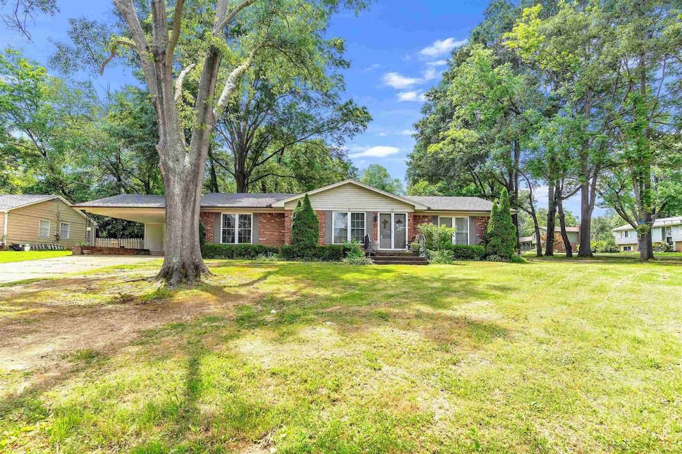 Single story home with concrete driveway, brick siding, a front yard, and an attached carport