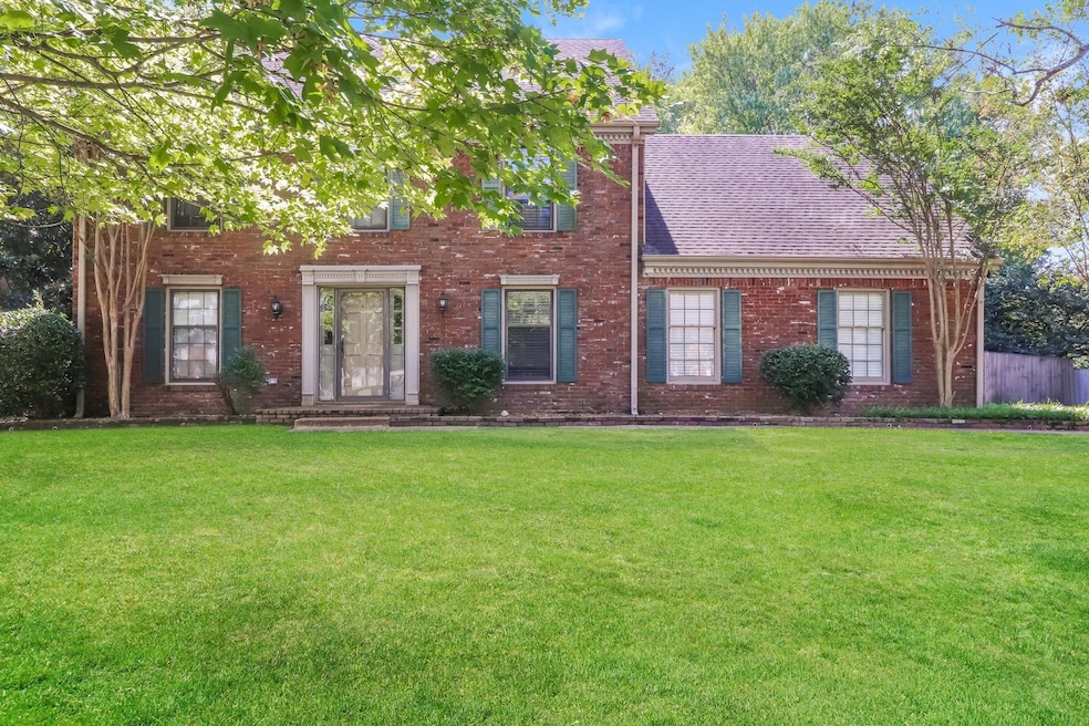 Colonial home with a front lawn, brick siding, and a shingled roof