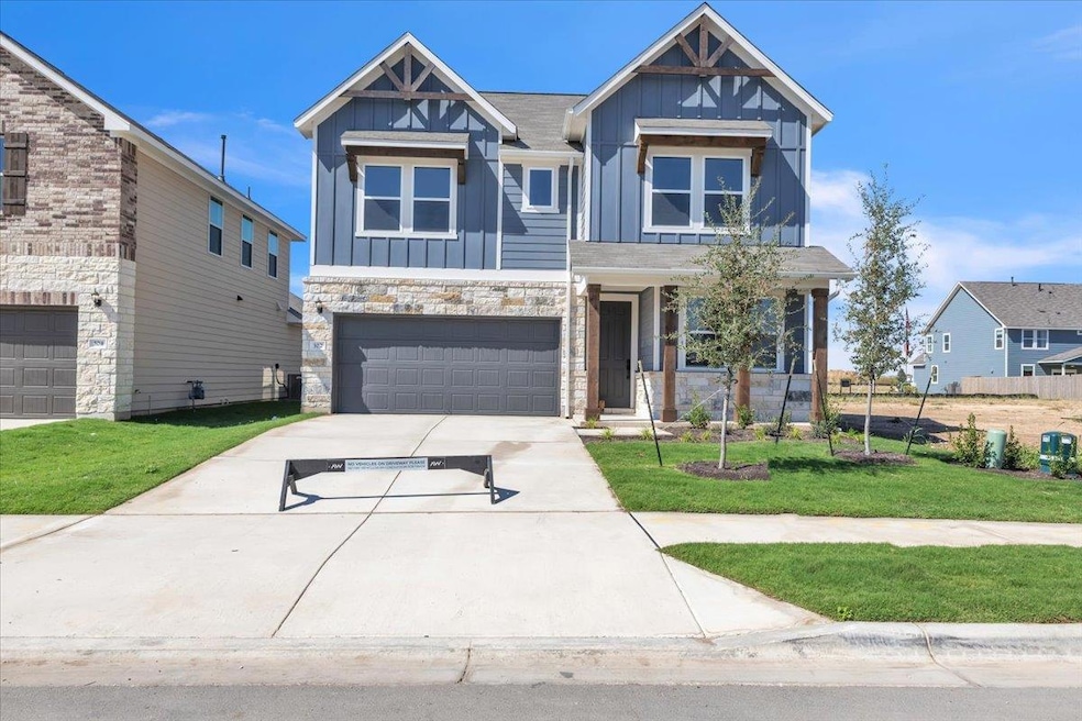 Craftsman-style home with board and batten siding, a front yard, driveway, and stone siding