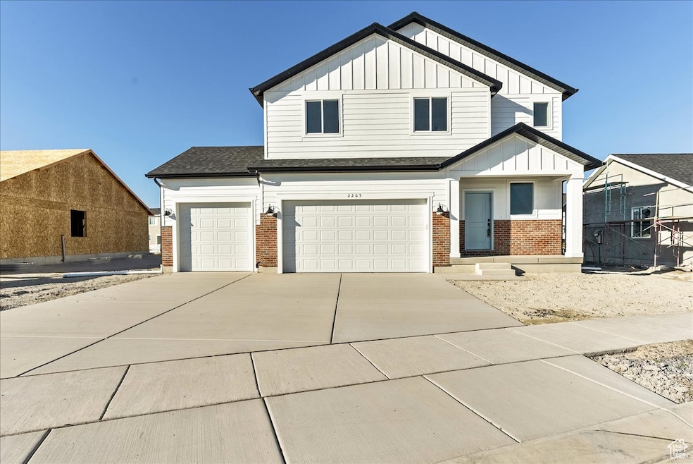 View of front of house featuring board and batten siding, brick siding, driveway, a garage, and a shingled roof