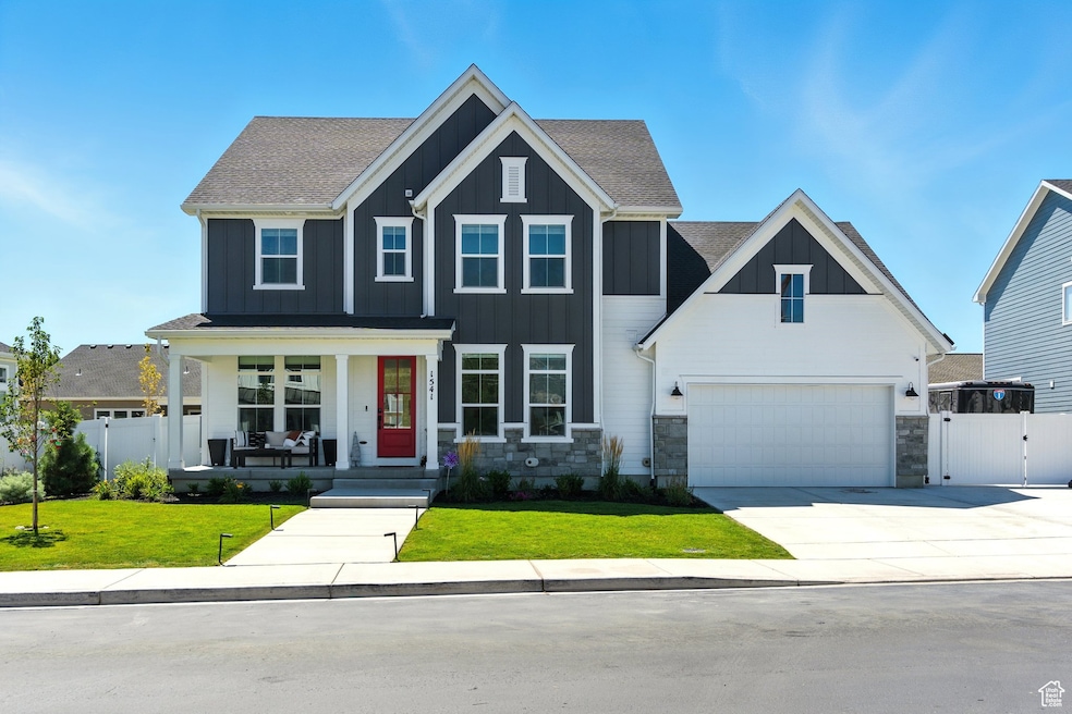 View of front of home with a gate, a porch, board and batten siding, driveway, and stone