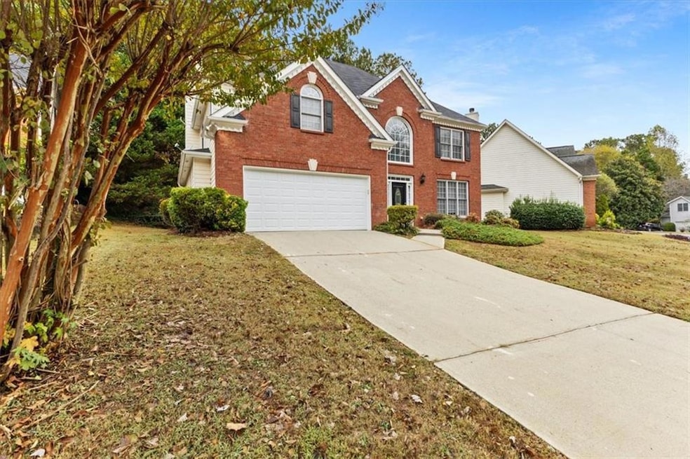 View of front of property featuring a front lawn, driveway, brick siding, and a garage