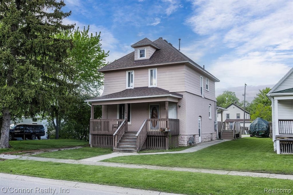 Traditional style home with a front lawn, roof with shingles, and covered porch