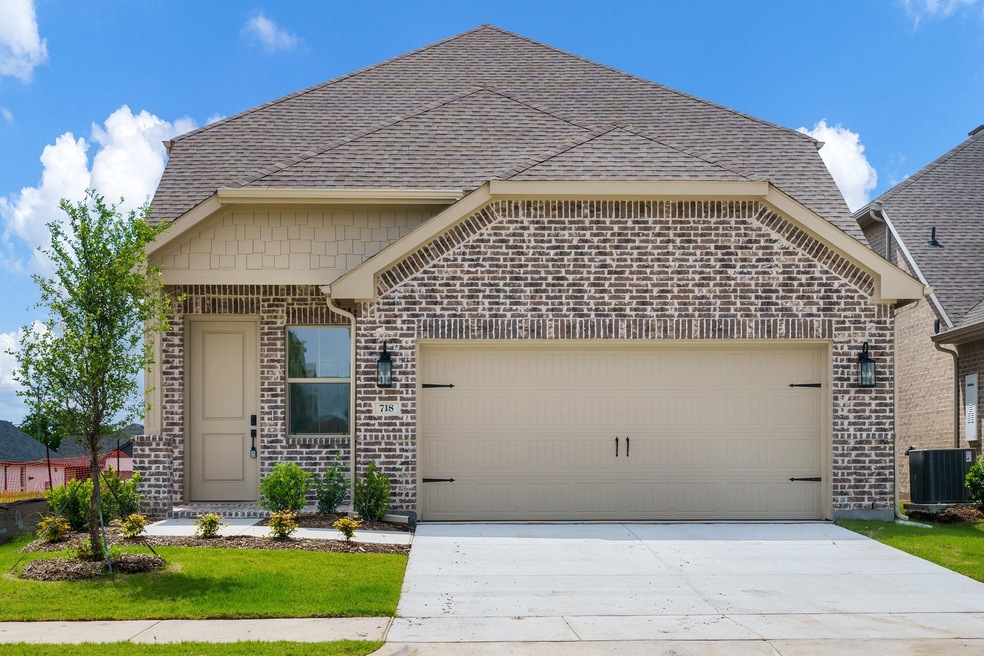 French country inspired facade with central AC, an attached garage, roof with shingles, and driveway