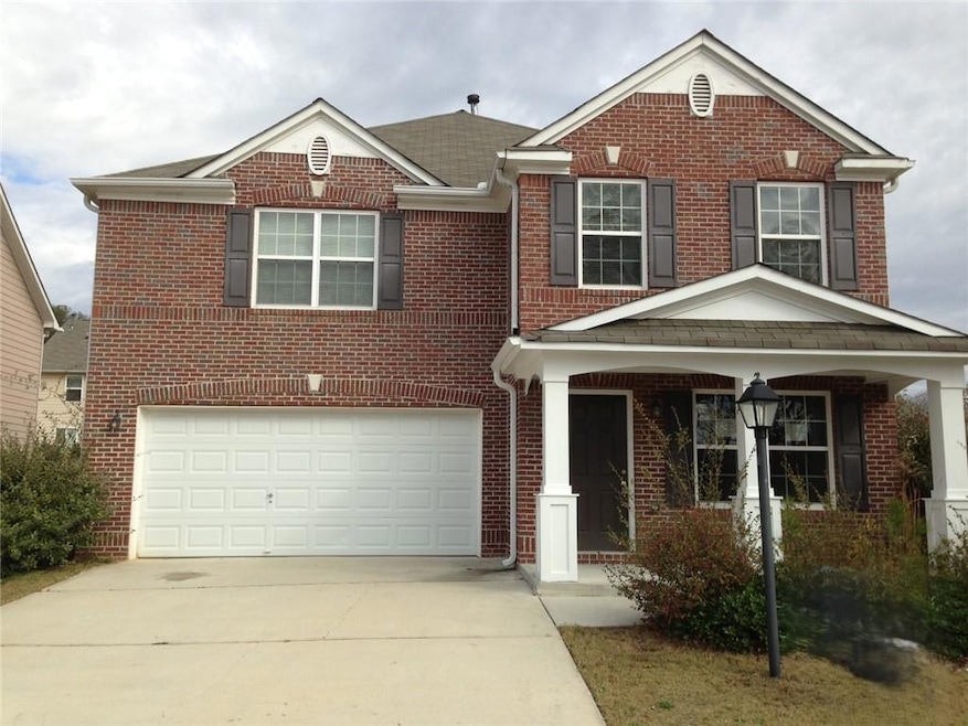 Traditional-style home featuring brick siding, concrete driveway, an attached garage, and covered porch.
