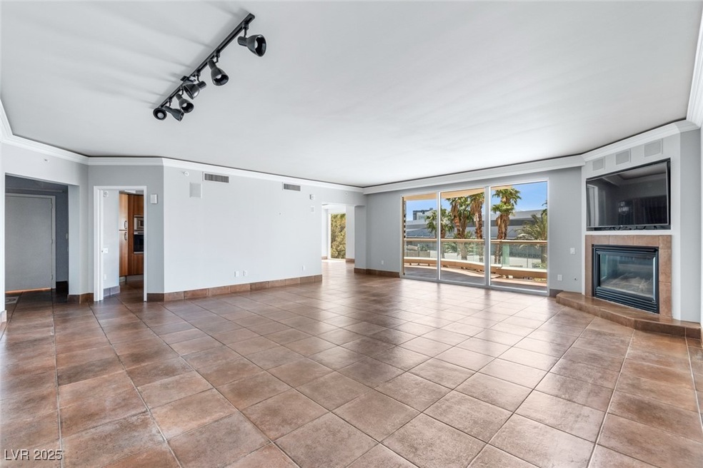 Unfurnished living room with crown molding, a tile fireplace, baseboards, and tile patterned floors