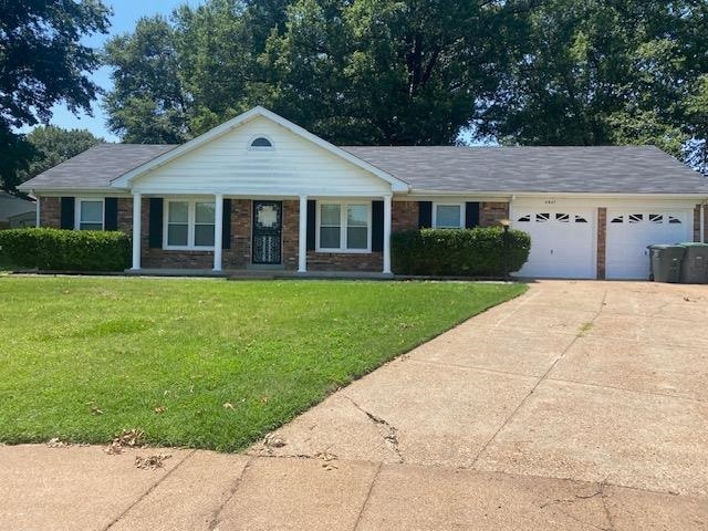 Ranch-style home with a garage, a front yard, driveway, brick siding, and a porch