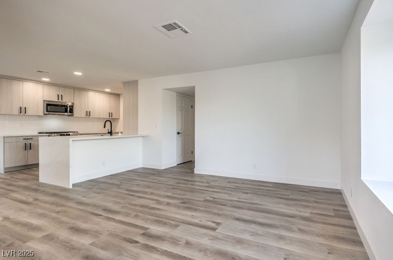 Kitchen featuring a sink, visible vents, light woo