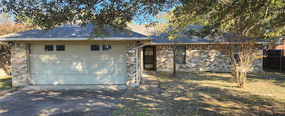 View of front of property featuring a shingled roof, brick siding, concrete driveway, and a garage