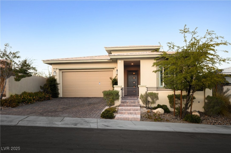 Prairie-style home with stucco siding, decorative driveway, and a garage