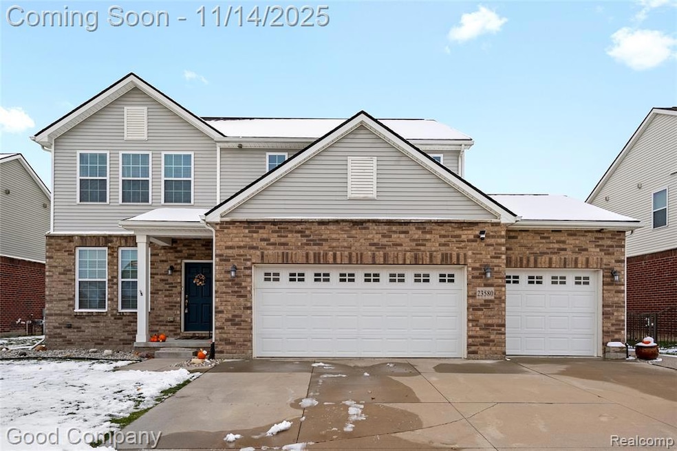 Traditional home with driveway, brick siding, and an attached garage