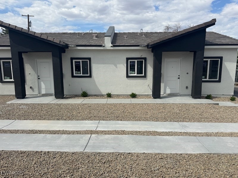 Ranch-style home with stucco siding and a tiled ro