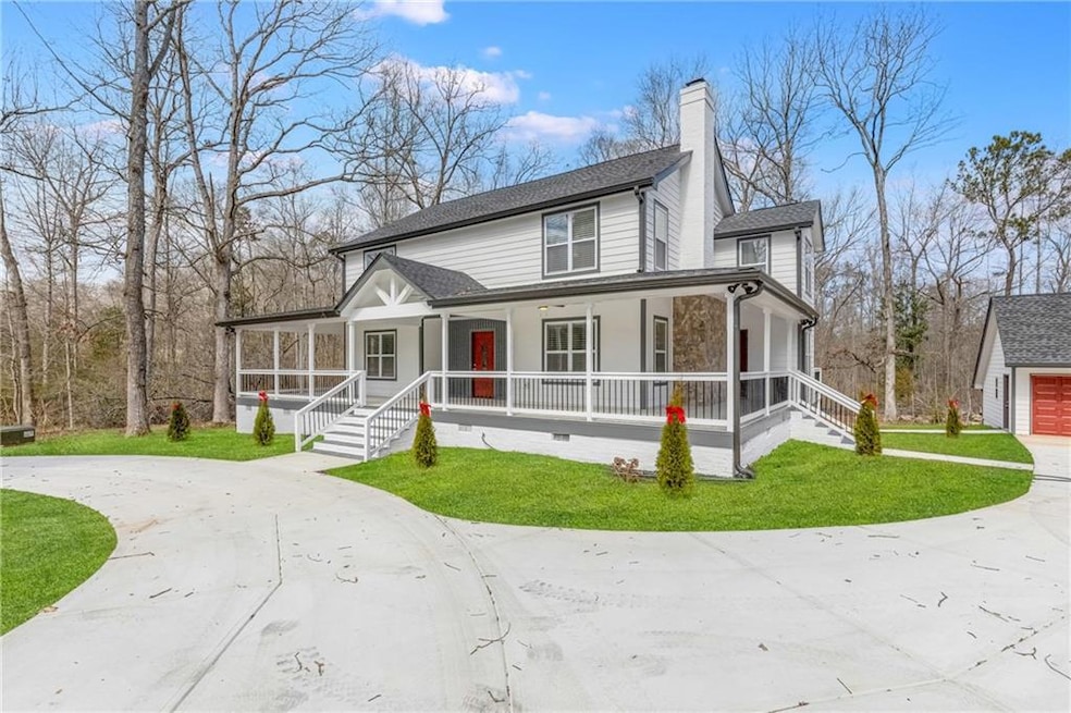 View of front of home with curved driveway, covered porch, a front lawn, a chimney, and a garage