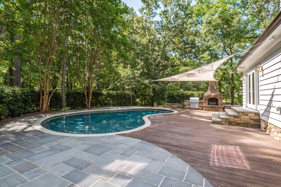 View of pool with an outdoor stone fireplace and a