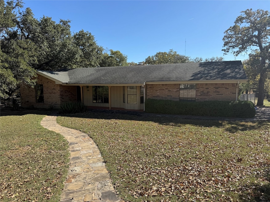 Ranch-style house featuring a front lawn, brick siding, and a shingled roof