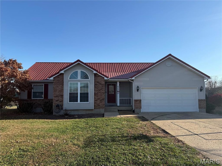 Ranch-style home with brick siding, a metal roof, driveway, and a front yard