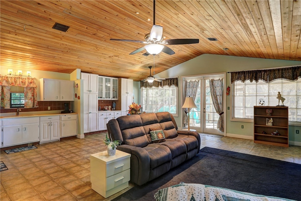 Living area featuring french doors, vaulted ceiling, wooden ceiling, and ceiling fan
