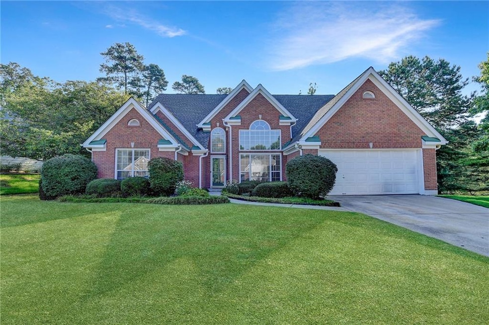 View of front of home with brick siding, driveway, a front yard, and an attached garage