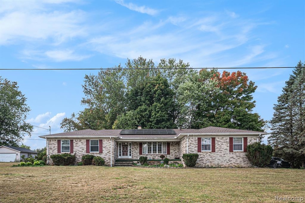 Ranch-style house with covered porch, a front yard, brick siding, and solar panels