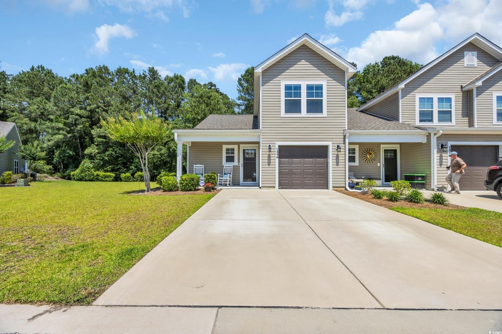 View of front facade with covered porch, a front lawn, a garage, concrete driveway, and roof with shingles