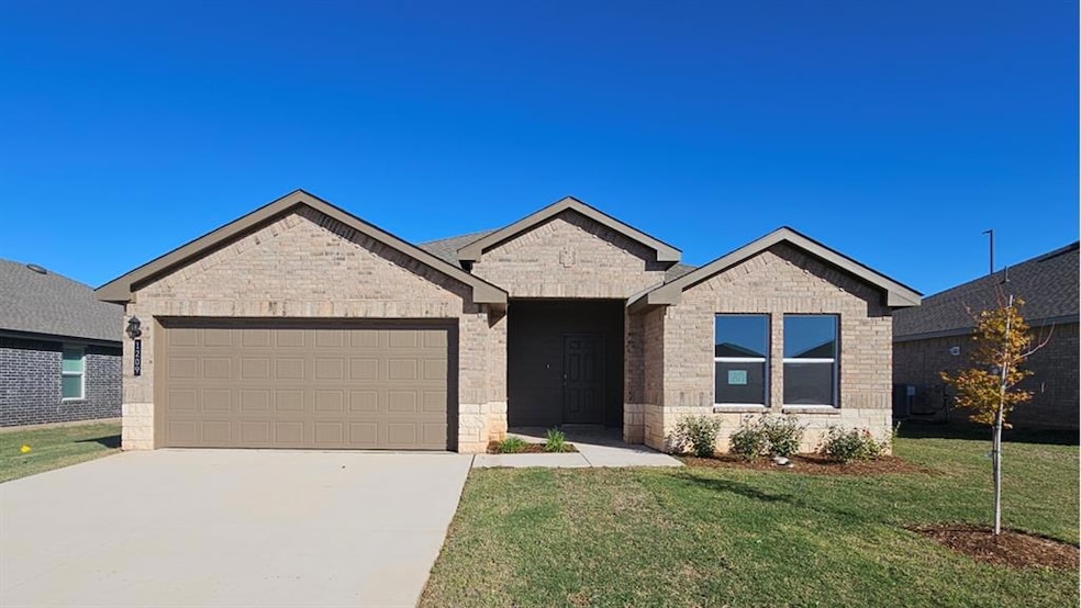 Single story home featuring a front lawn, concrete driveway, a garage, and brick siding