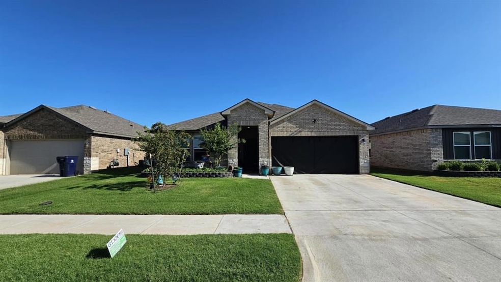 Ranch-style home with brick siding, an attached garage, a front yard, and concrete driveway