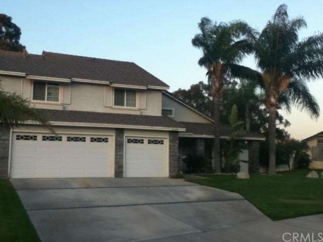 Front of home surrounded by palm trees and landsca