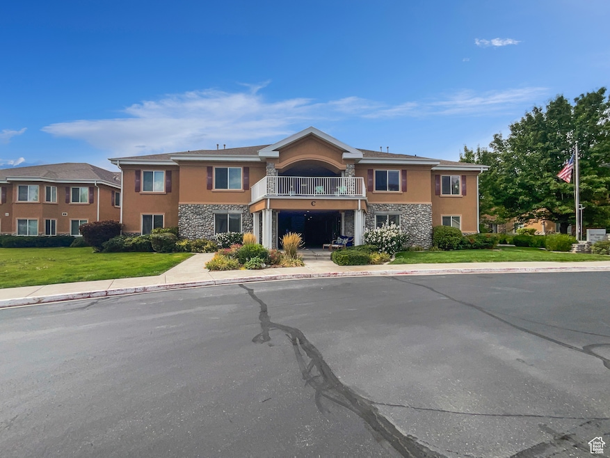 View of front of house featuring a balcony, stone siding, and stucco siding