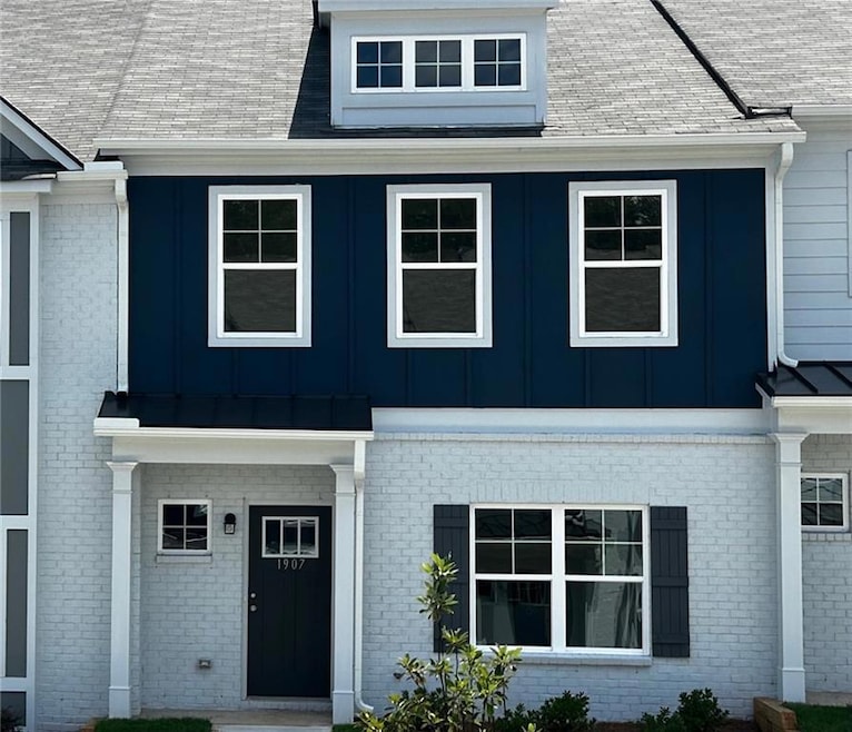 View of front of house featuring brick siding, board and batten siding, and a shingled roof