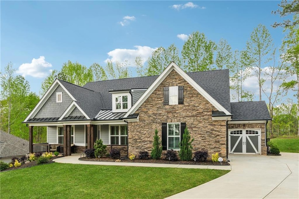 Craftsman house featuring driveway, stone siding, a porch, and a garage