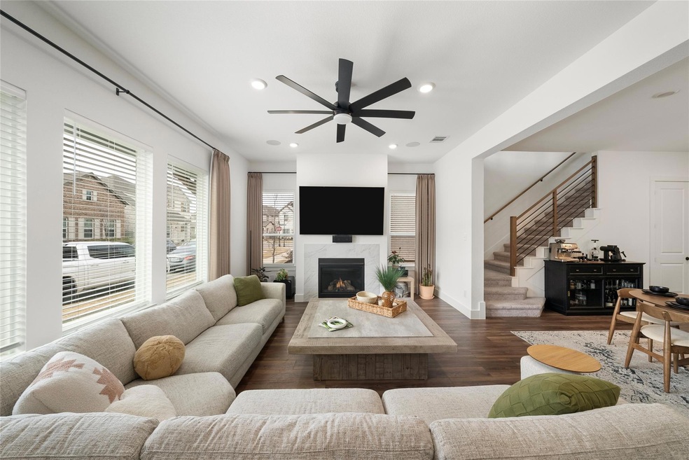 Living room featuring ceiling fan, a high end fireplace, and dark hardwood / wood-style floors
