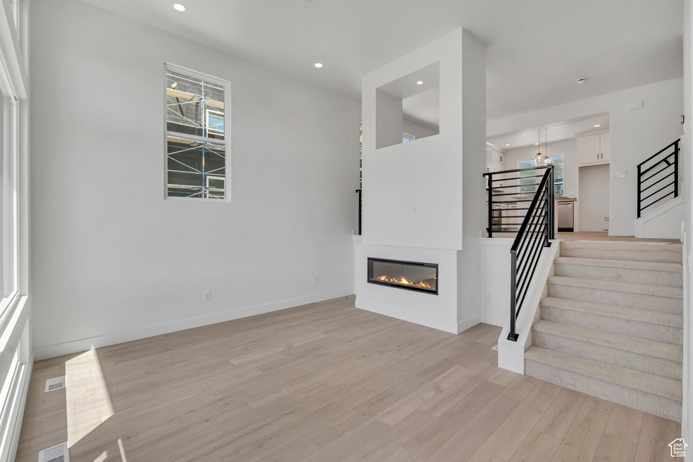 Staircase with a glass covered fireplace, recessed lighting, and wood finished floors
