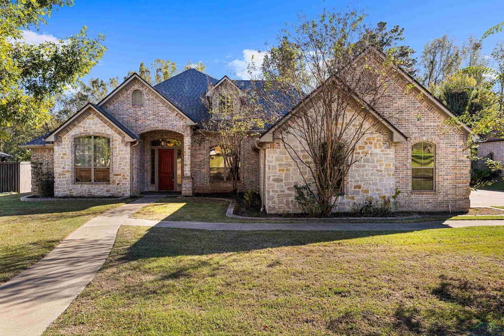French provincial home with stone siding, a front yard, and brick siding