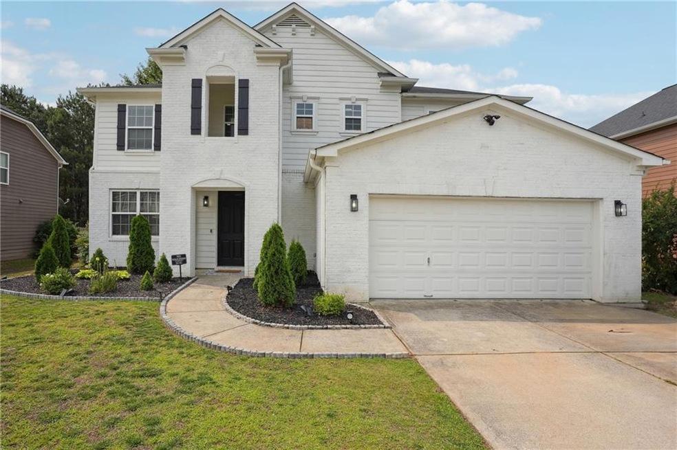 View of front of house with brick siding, an attached garage, driveway, and a front yard