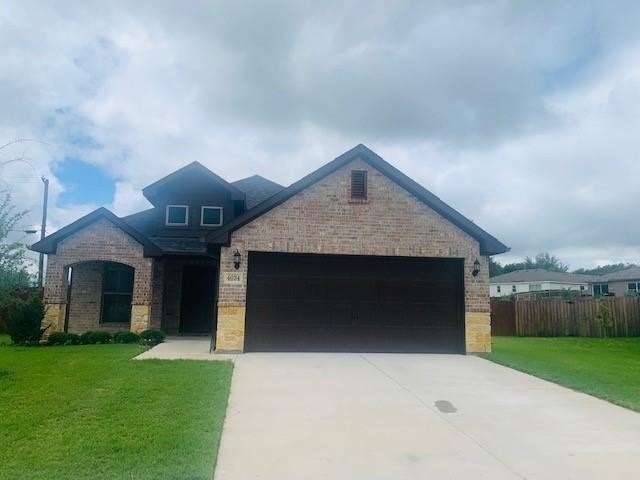 View of front of house with brick siding, an attached garage, and concrete driveway