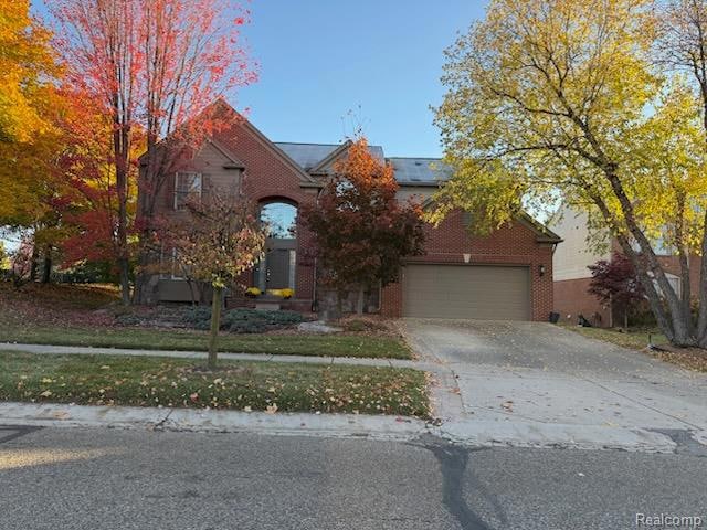 View of front of home featuring brick siding, driveway, and a front yard