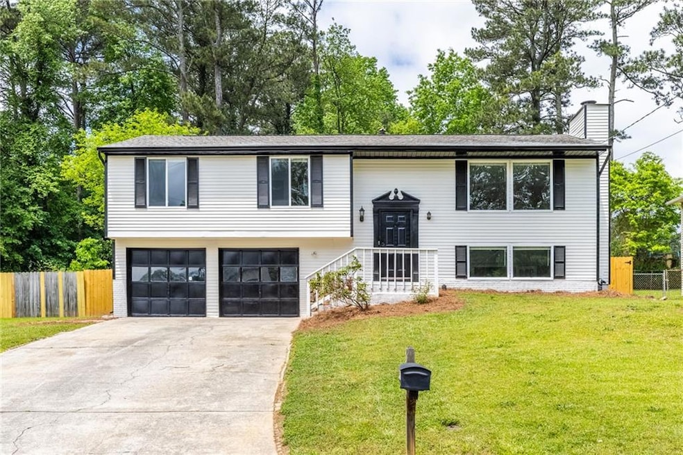 Raised ranch featuring driveway, fence, a front ya