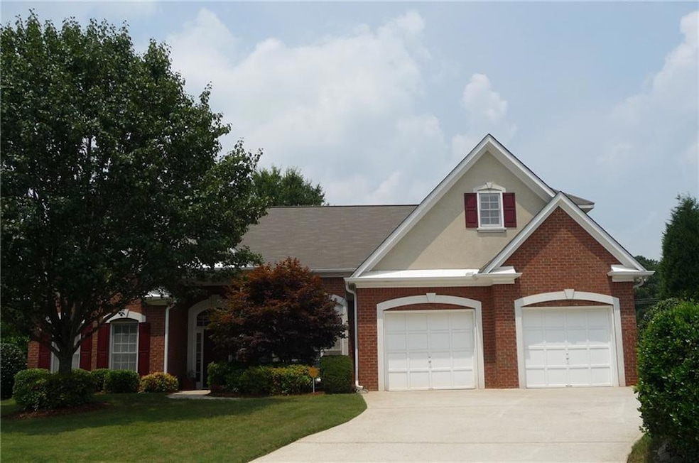 View of front facade with brick siding, driveway, a garage, and a front lawn