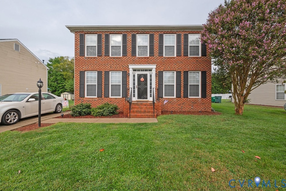 Colonial inspired home featuring brick siding and a front lawn