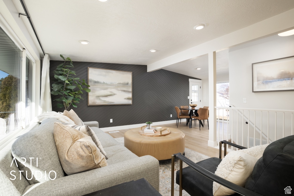 Living area featuring an accent wall, wood finished floors, wooden walls, beamed ceiling, and recessed lighting